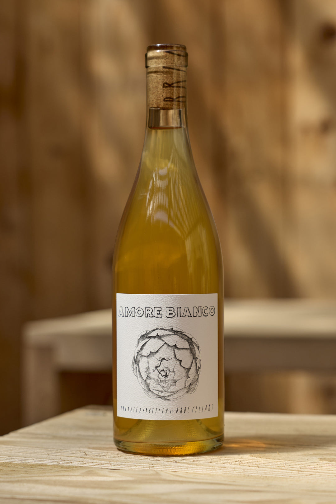 A bottle of 2025 Amore Bianco skin contact Tocai Friulano wine with a label featuring an illustration of an artichoke.