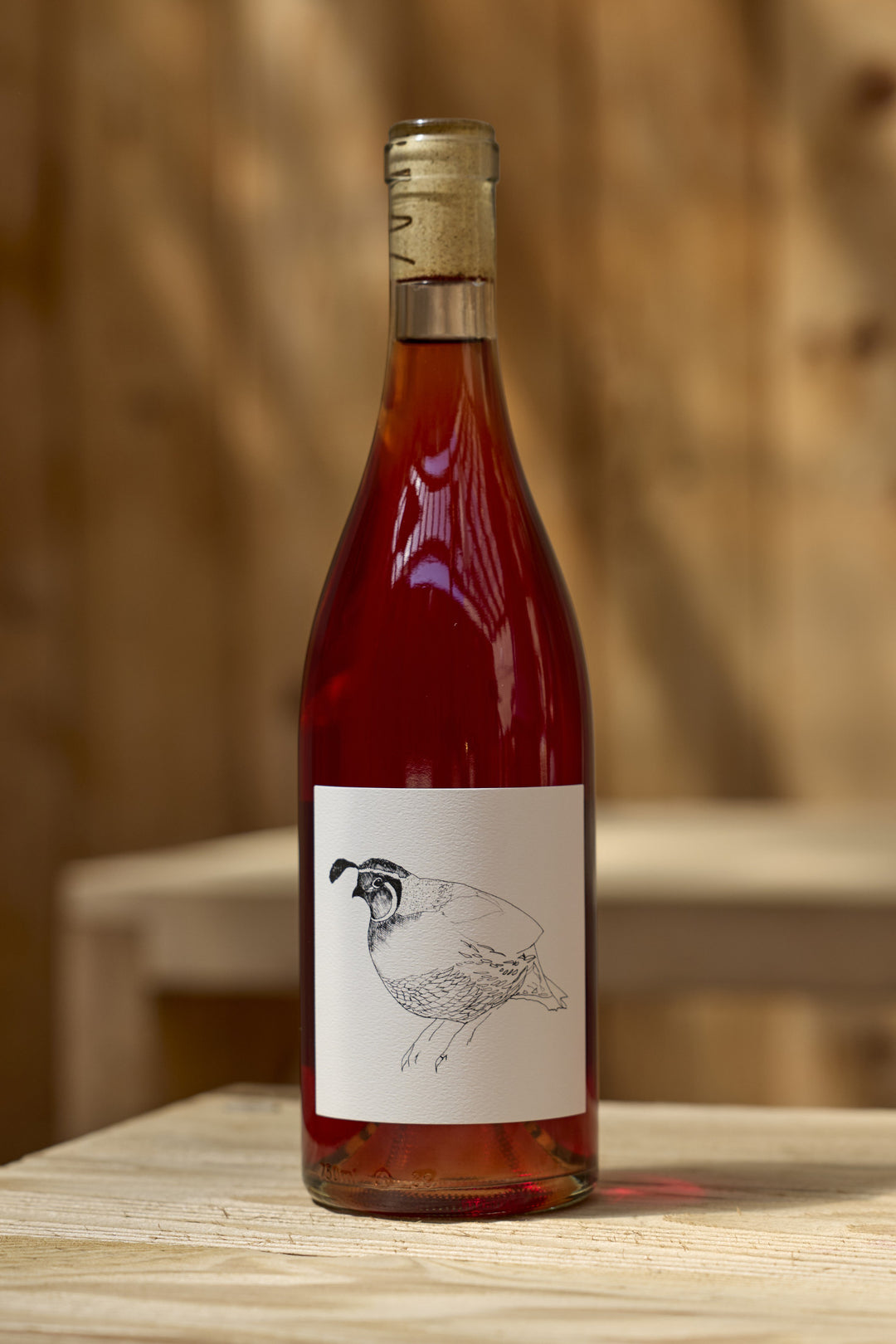 A bottle of 2023 Grenache Gris by Broc Cellars, a rose-colored wine with a white label featuring a line drawing of a quail.