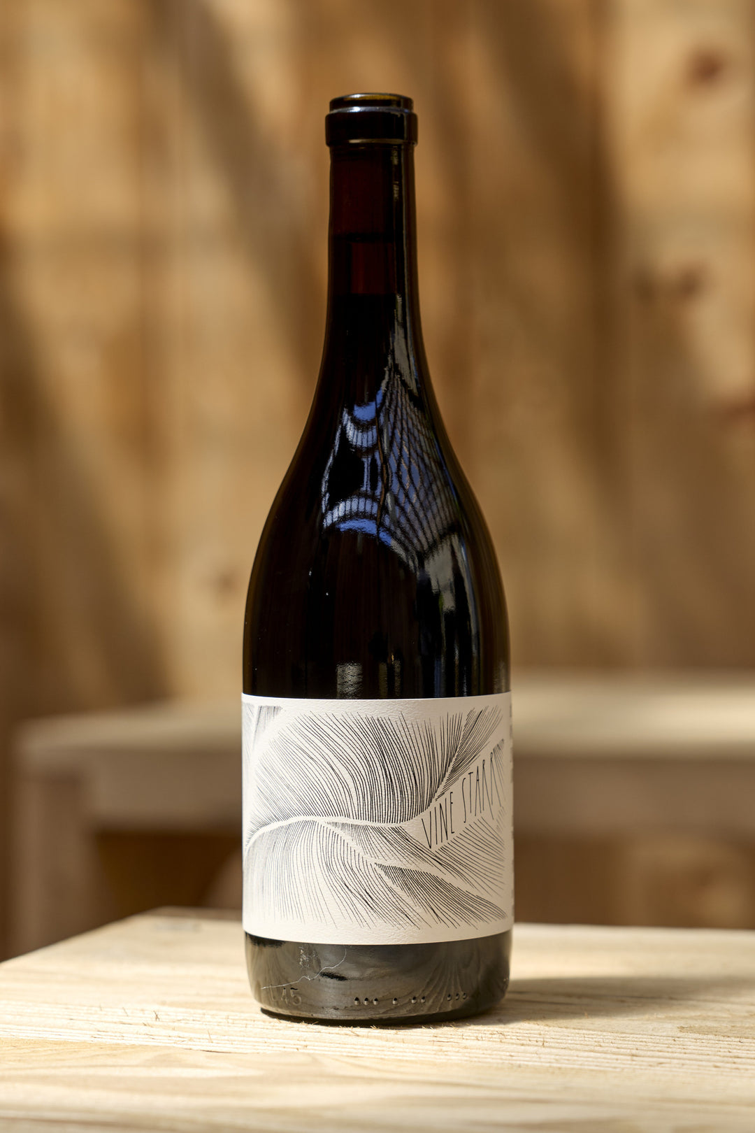 A dark glass bottle of 2023 Vine Starr Zinfandel with a cream-colored label featuring a black-and-white botanical sketch.