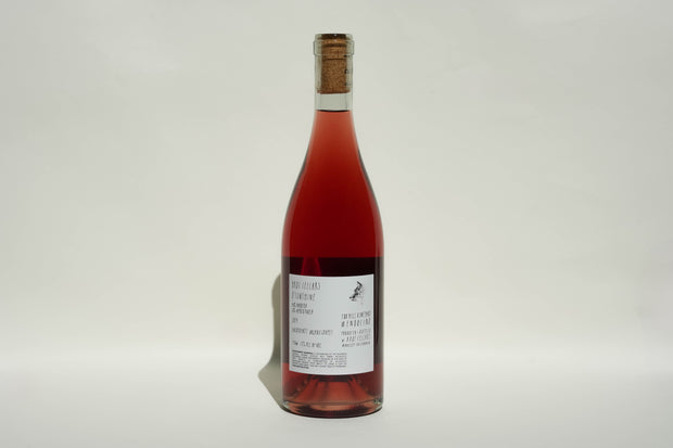 A clear glass wine bottle with a cork, filled with red wine, features a white label with black text and graphics reading 2024 Oh Sunshine by Broc Cellars. The background is plain and light-colored.