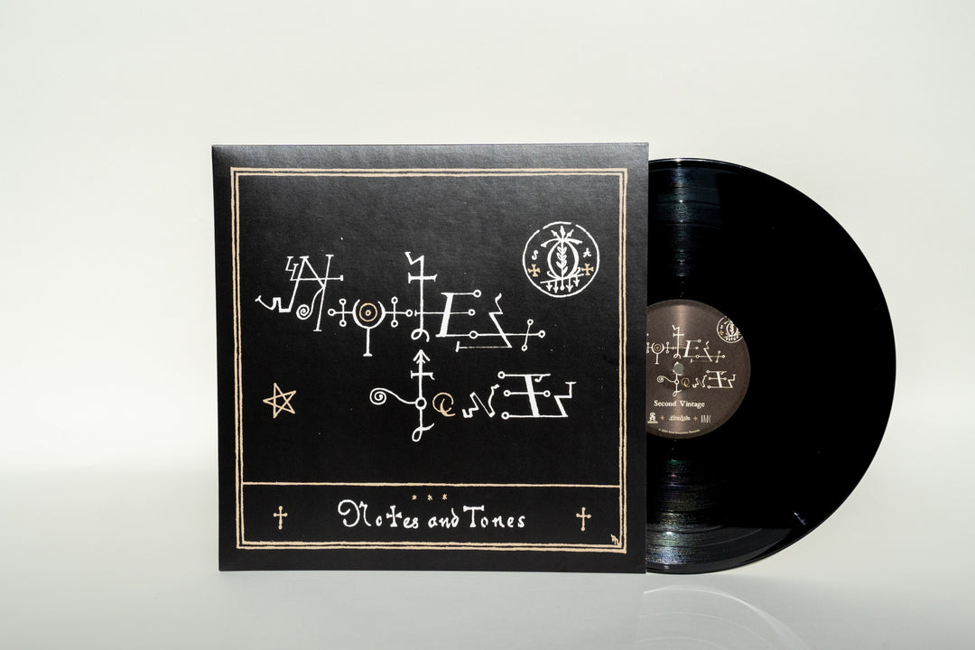 A black vinyl record partially slides out of its matching black sleeve, featuring white abstract symbols and the title Notes &amp; Tones V.2 - The Album at the bottom. This unique edition from Broc Cellars marks a collaborative release with DJ Muggs, infusing artistry into each groove.