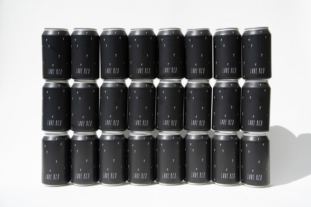 Twenty Broc Cellars Love Red Can Packs with black labels, arranged in four rows on a white background; each can displays “LOVE RED” in bold white letters and features California red wine crafted from old heritage vines.