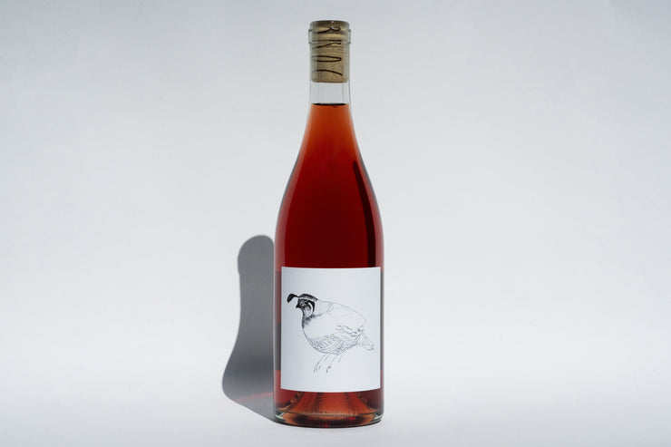 The 2023 Grenache Gris by Broc Cellars is a rosé wine from Mendocino County, featuring a cork top and a bird line drawing on the label. The bottle casts a shadow on the plain light gray background, hinting at its unique carbonic maceration process.