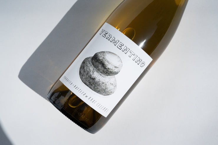 A wine bottle rests sideways on a light backdrop, labeled 2023 Fox Hill Vermentino with a textured stone-like illustration, indicating its prestigious origin from Broc Cellars and Fox Hill Vineyard in Mendocino. It contains white wine.