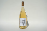 The 2024 Got Grapes White from Broc Cellars stands proudly with a cork, featuring a whimsical grape character on its label exclaiming Eat Grapes. Made from Orange Muscat, it shines against a plain, light-colored background.