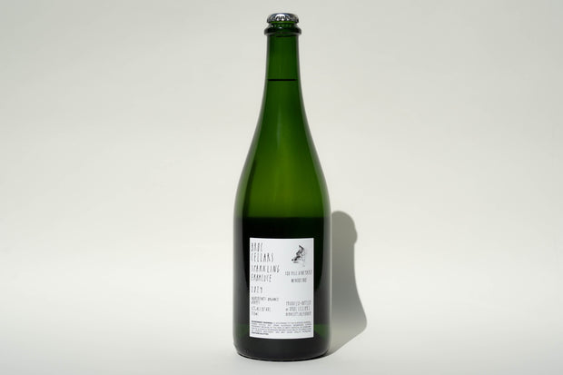 A 2024 Sparkling Erbaluce by Broc Cellars, with a white label featuring text and a simple logo saying Coming Soon, stands against a plain background. The green wine bottle has a wire cage on the cork, indicating its sparkling wine.