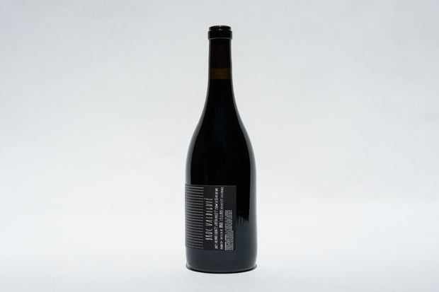 A tall, dark bottle of 2023 Broc Valdiguié by Broc Cellars stands against a light gray background, highlighting its narrow neck and black cap. The label subtly suggests its origin from the heritage vines of Wirth Ranch and the rich Valdiguié grape.