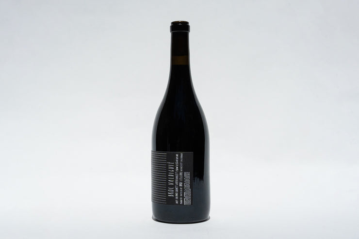 A tall, dark bottle of 2023 Broc Valdiguié by Broc Cellars stands against a light gray background, highlighting its narrow neck and black cap. The label subtly suggests its origin from the heritage vines of Wirth Ranch and the rich Valdiguié grape.