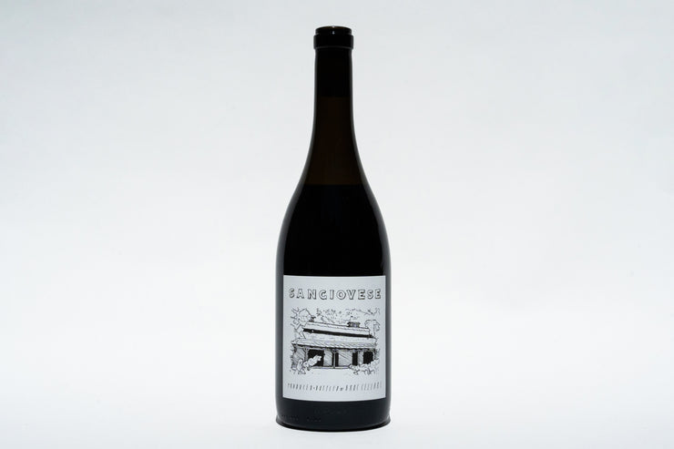 A dark glass bottle of 2023 Sangiovese wine from Broc Cellars features a label with a black and white house and landscape illustration resembling Fox Hill Vineyard, set against a plain white background.