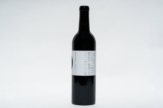 A black wine bottle with a white label stands against a plain white background, featuring minimalist black text and abstract shapes. The 2023 Broc Massa Cabernet Sauvignon from Broc Cellars in California is sealed with a black cap, highlighting its organic roots.