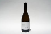 A dark glass wine bottle with a light label stands upright against a plain background. The minimalist font Happī Chenin suggests its Broc Cellars origin. This organic 2023 Chenin Blanc is perfectly centered in the image.