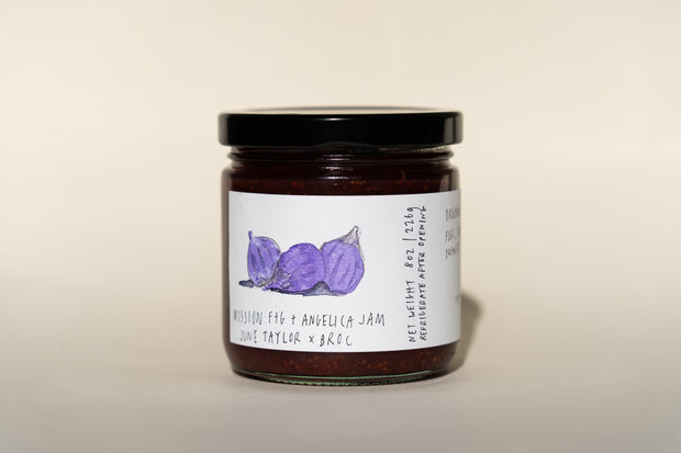 The June Taylor Mission Fig + Angelica Jam by Broc Cellars comes in a glass jar with a black lid, adorned with fig illustrations and the text Rose + Taylor x Broc. It weighs 8 oz (226g) and is crafted in the USA, ideally pairing with Broc Angelica wine.