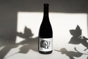 The 2014 NERO D’ AVOLA by Broc Cellars features a label with a black and white image of an upright badger on a light surface, framed by sharp leaf shadows, elegantly contrasting the well-lit scene. Its design echoes its origins from Fox Hill Vineyard in Mendocino.