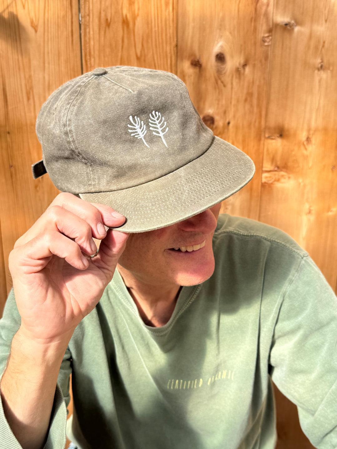 The faded olive brushed cotton twill Fox Hill Field Hat features two white embroidered plant icons on the front and an adjustable strap.