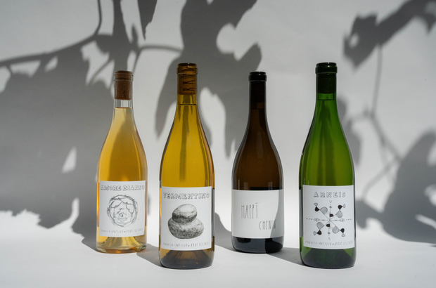 Four Broc Cellars 2025 FALL CLUB- CHILLABLE LITES wine bottles stand on a white surface with shadows behind. Each bottle, including Amore Bianco and Vermentino, has a white label featuring simple black illustrations and text.