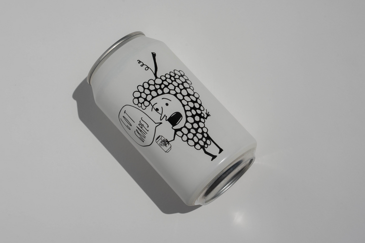 A Got Grapes Red Can by Broc Cellars, featuring a black illustration of grapes holding a drink and saying No worries on a white can, is photographed on a plain white surface. Coming soon.