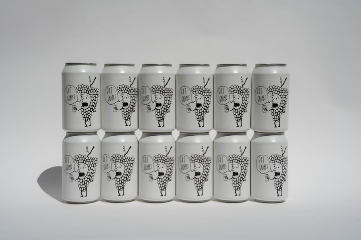 Twelve white cans featuring black line art of a stylized animal with antlers and geometric shapes are arranged in three rows of four. Each can displays “Broc Cellars Got Grapes Red Can Pack,” a chillable red Grenache blend.