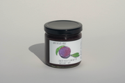A glass jar with a black lid holds a dark purple spread. The label features a plum and reads “June Taylor x Fox Hill Santa Rosa Plum w/ Bay” by Broc Cellars—a handmade preserve celebrating rich, fruity flavors.