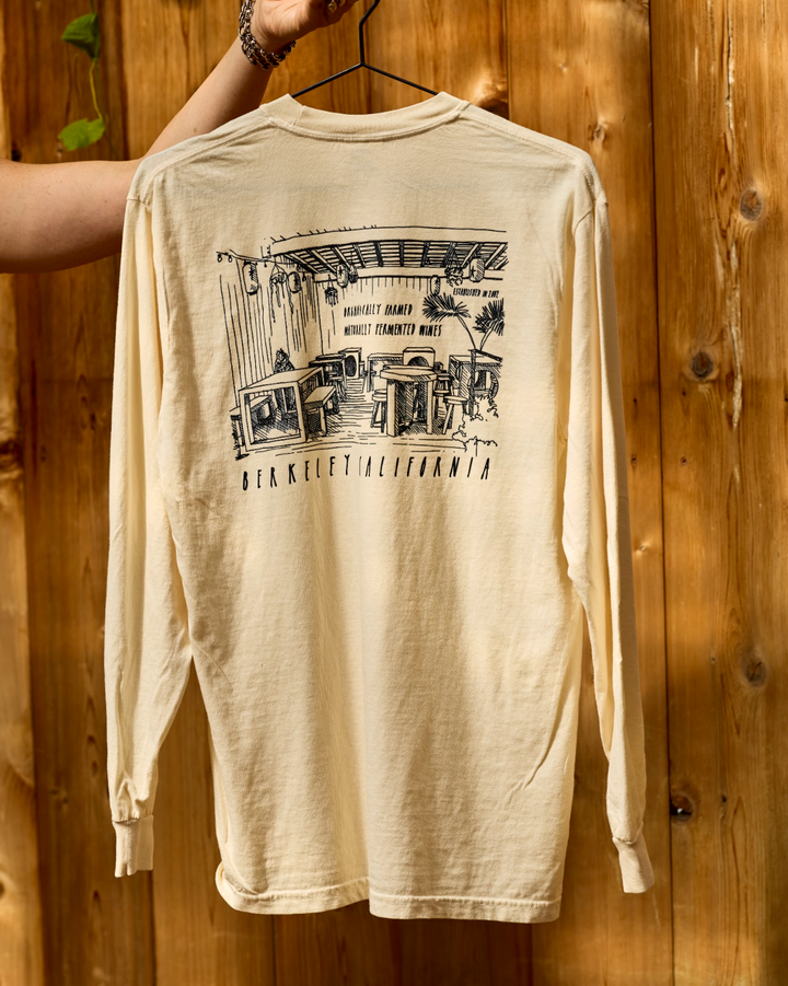 Cream-colored long-sleeve Berkeley Long Sleeve tee featuring a black line-drawing of a restaurant interior and the text Berkeley California on the back.