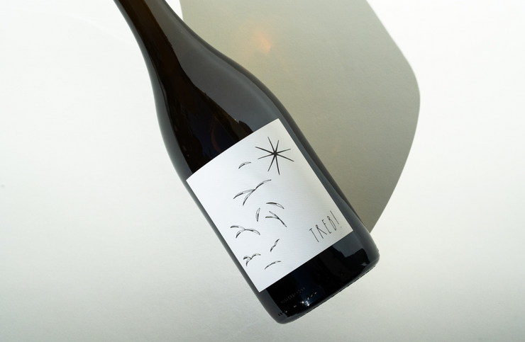 A dark bottle with a minimalist white label displays abstract black birds, a star, and the word FINCA. On the white surface lies Broc Cellars 2023 Treb!, hinting at the skin-contact Trebbiano inside—a true Amore Bianco experience.