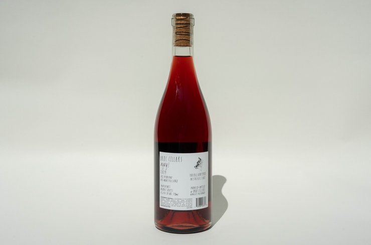 A clear glass bottle of 2024 Ayay! red wine from Broc Cellars, sealed with a cork and featuring a white label with black text, stands upright against a plain white background.