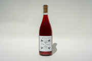 A clear glass bottle of red wine with a cork, labeled 2024 Ayay! by Broc Cellars. The white label shows AVAY! above a black and white artichoke illustration, set against a plain light background.