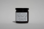 A small glass jar with a black lid and white label lists wild cherry plum, orange, rosemary, and sugar. Broc Cellars June Taylor x Fox Hill Wild Cherry Butter is a hand-made preserve with the website also shown on the label.