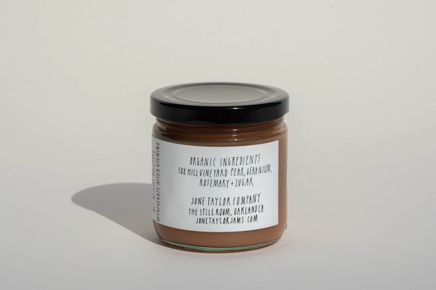 A small glass jar with a black lid contains Broc Cellars’ June Taylor Fox Hill Pear, Lemon Geranium, and Rosemary Preserve, made in small batches with organic ingredients. The white label notes: June Taylor Company, Oakland, CA.