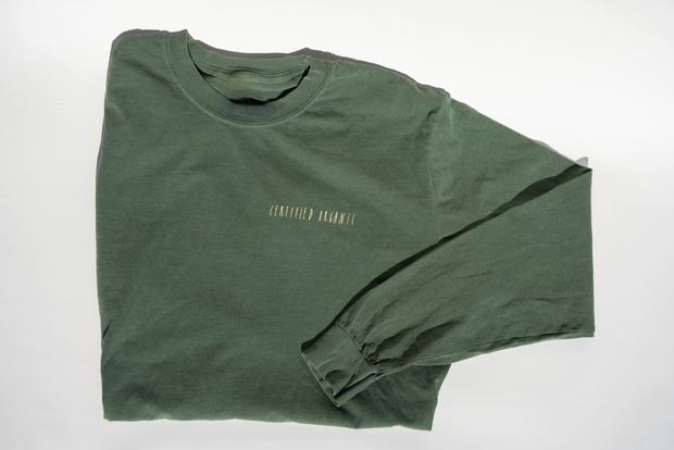 The Fox Hill Organic Long Sleeve Shirt by Broc Cellars, in forest green and made from 100% cotton, is laid flat on a white surface. Small, centered chest text reads CERTIFIED HUMAN.