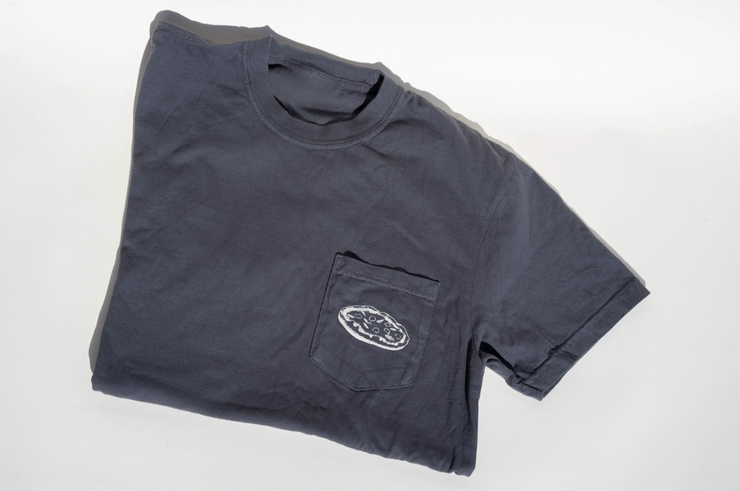A folded dark gray Broc Amore Rosso T-Shirt by Broc Cellars features a small white oval "Broc Pocket Pizzeria" graphic on the front pocket, displayed on a plain white background.