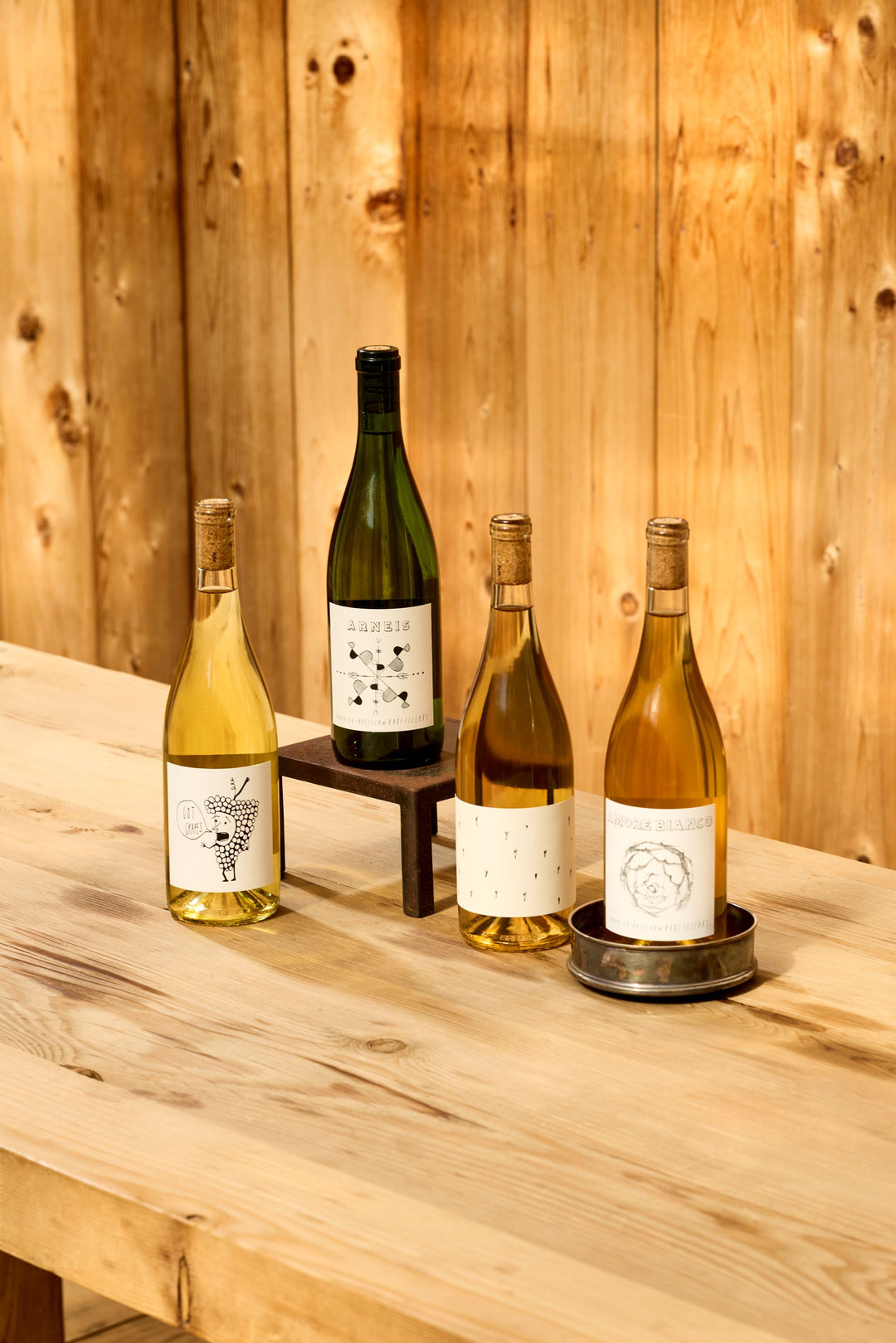 Four bottles of Broc Cellars Fresh Whites Pack white wine standing on a wooden table.