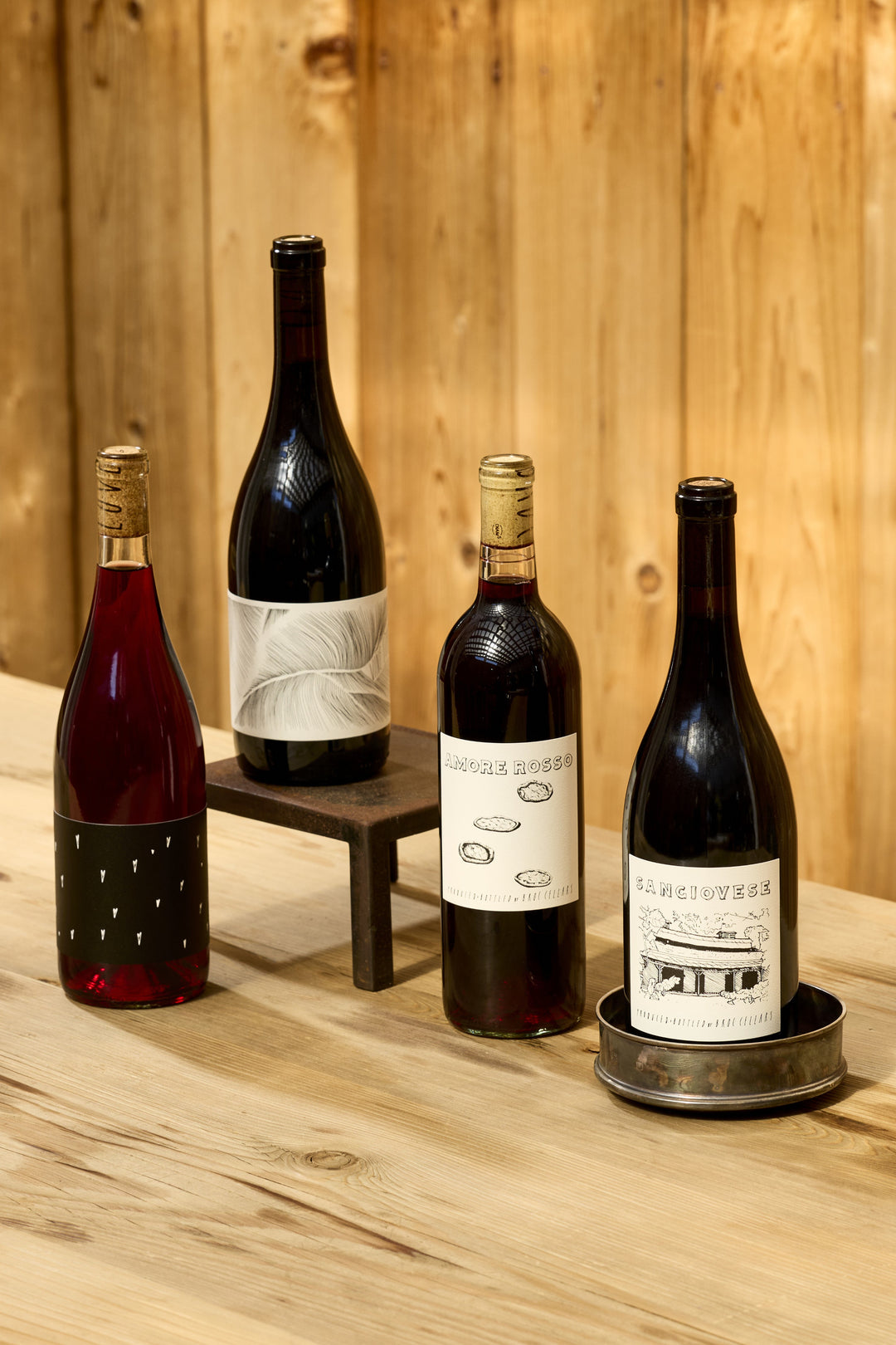 Four bottles of Broc Cellars Essential Reds Pack balanced red wine arranged on a wooden surface as the perfect pasta wine.