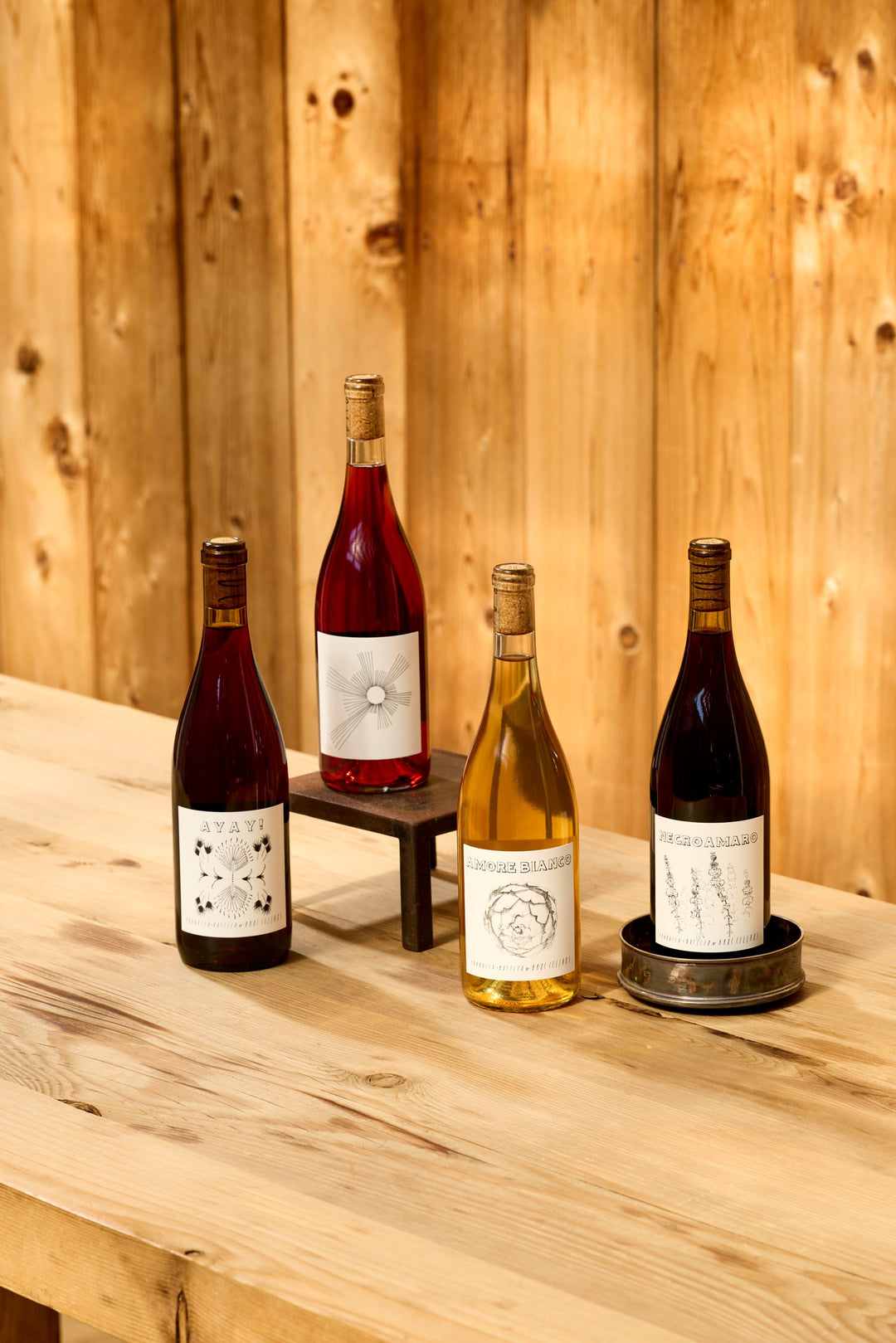 Four bottles of Broc Cellars Chillable 4-Pack skin-contact whites and light reds with illustrated labels on a wooden table.