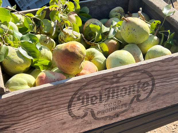 A wooden crate filled with ripe, speckled pears, some with leaves attached, features the Del Monte logo and Food Products text. Ideal for crafting pear butter using organic ingredients, like June Taylors Fox Hill Pear Butter featuring lemon geranium and rosemary by Broc Cellars.