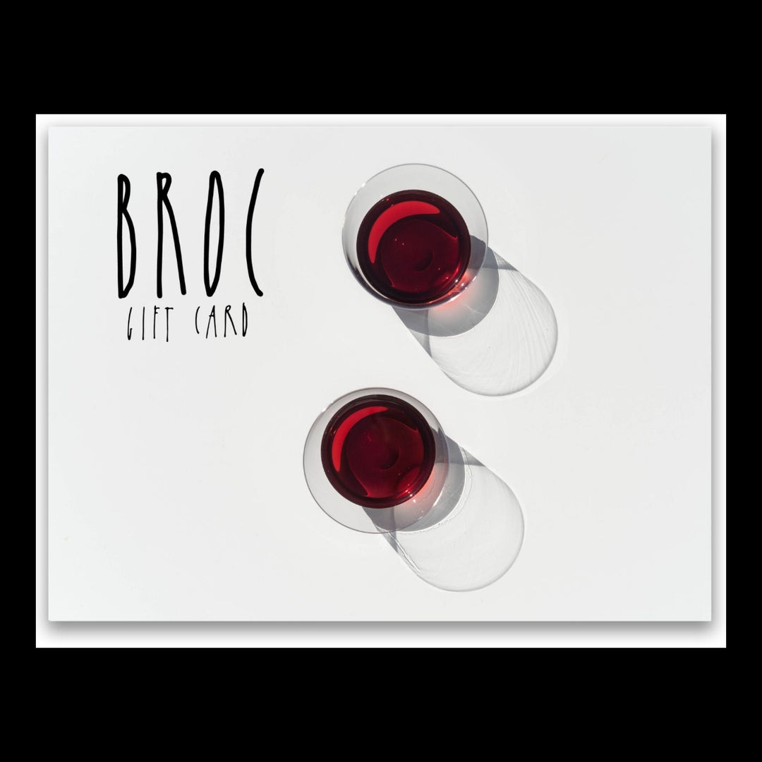 Two glasses of red wine cast shadows on a white surface, with Broc Gift Card text on the left. Ideal for a refined online shopping experience, this digital gift card from Broc Cellars is perfect for your next special occasion.