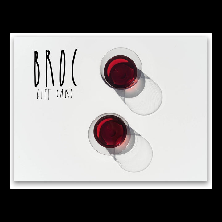 Two glasses of red wine cast shadows on a white surface, with Broc Gift Card text on the left. Ideal for a refined online shopping experience, this digital gift card from Broc Cellars is perfect for your next special occasion.