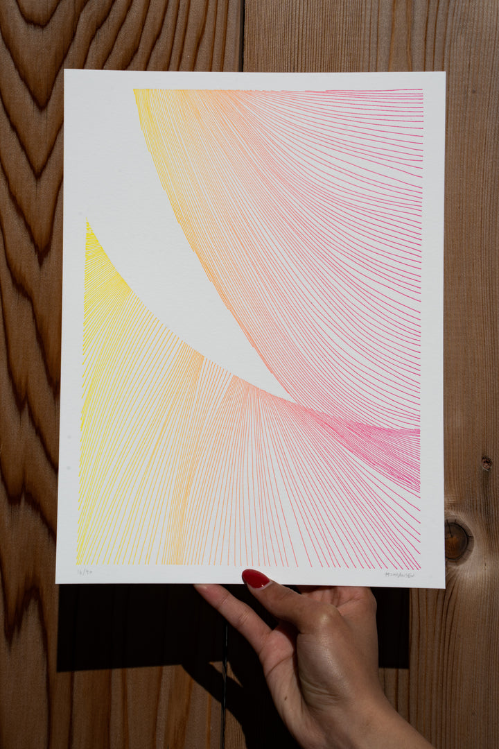 Red-polished nails hold a piece of Martas Prints from Broc Cellars against a wooden wall. Designed by Marta Johansen, it features intersecting lines in yellow, orange, and pink on luxurious cotton rag, showcasing a gradient effect. Its an exclusive part of her limited edition collection.